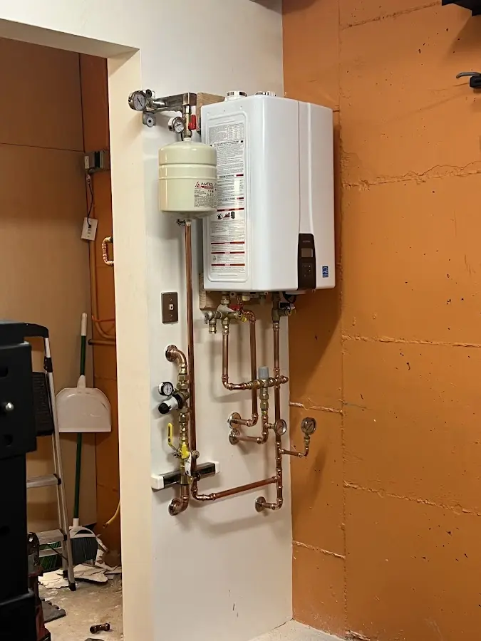 Plumbing technician inspecting water heater connections in North Canton